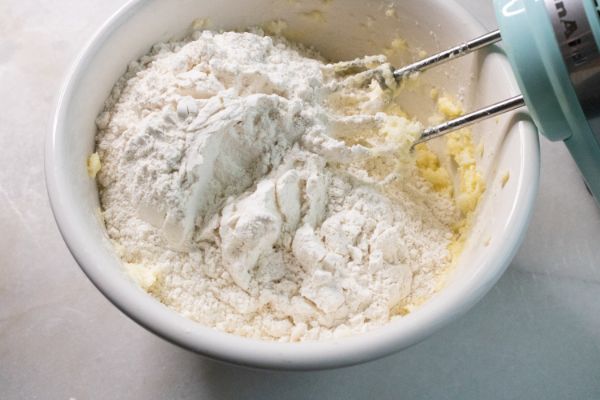 adding flour to peppermint snickerdoodles batter in a bowl with a mixer