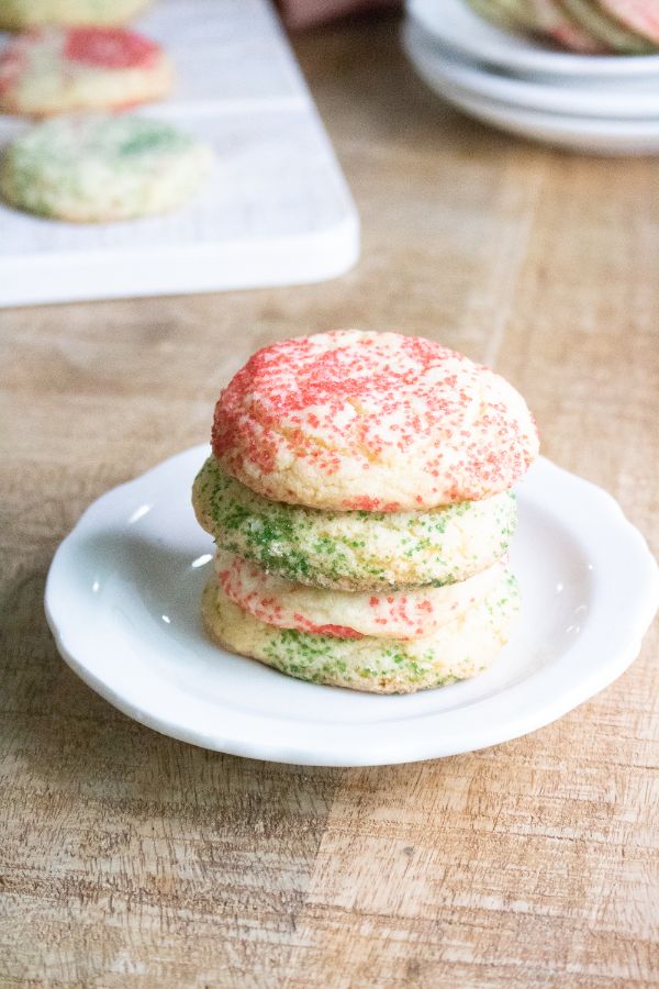 stack of peppermint snickerdoodles on a white plate on a table with more cookies in the background