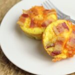 easy bacon and egg cups on a plate with a tan background