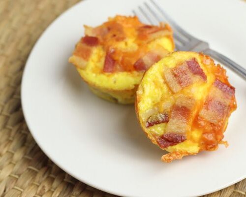 easy bacon and egg cups on a plate with a tan background