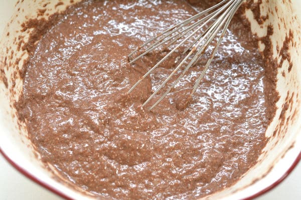 a whisk in a mixing bowl being used to stir chocolate protein chia pudding