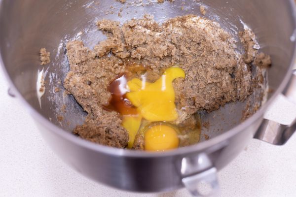 a metal mixing bowl with brown sugar, butter, eggs and vanilla in it