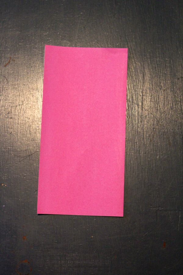 pink origami paper folded in half on a dark brown background