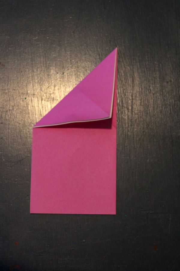 pink origami paper folded on a dark brown background