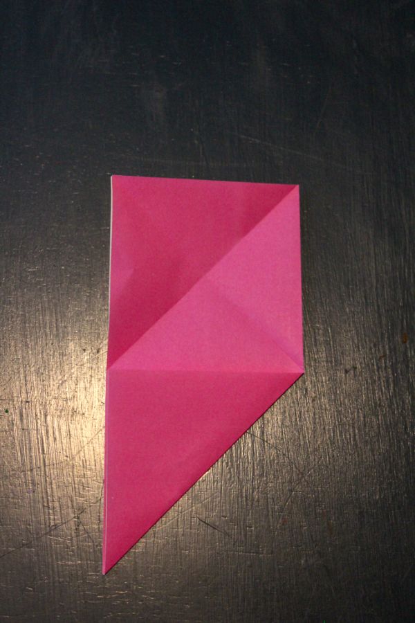 pink origami paper folded on a dark brown background