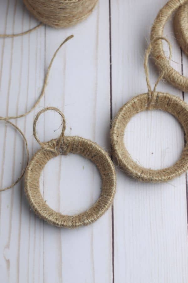 mason jar lid rings wrapped in twine next to a ball of twine on a white wood table