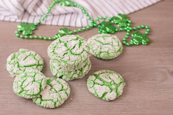 green cookies on a brown table with green beads with clovers on them and a cloth in the background