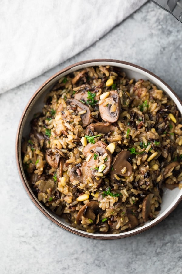 overhead view of wild rice pilaf in a brown and white bowl on a gray background