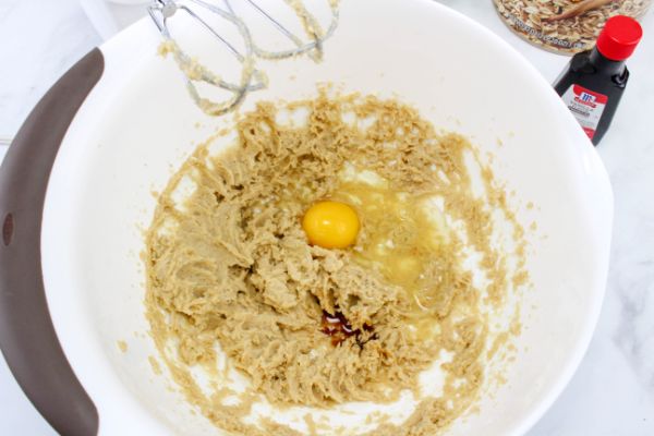 Egg and vanilla added to wet mixture in white mixing bowl