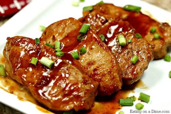 bbq pork chops topped with sliced green onions on a white plate