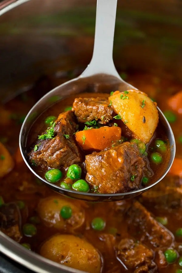 a spoon of beef stew above an instant pot full of beef stew