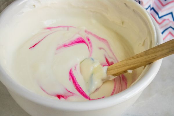 sweetened condensed milk and peppermint extract in a white bowl with a spatula in it