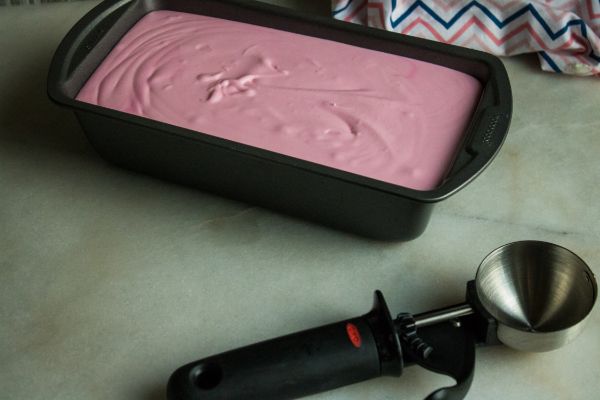 the best peppermint ice cream in a loaf pan on a counter next to an ice cream scoop