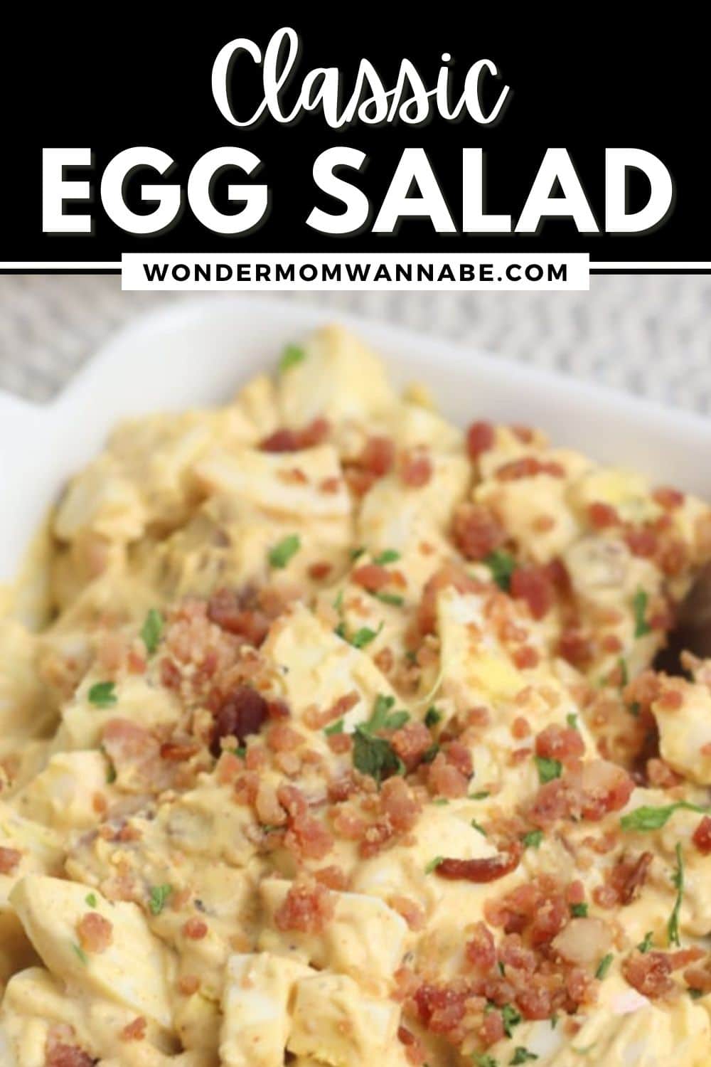 A bowl of classic egg salad topped with bacon bits and garnished with fresh herbs, with the text "classic egg salad recipe" and the website "wondermomwannabe.com" displayed above