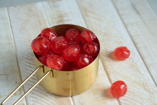 candied cherries in a measuring cup and on the table