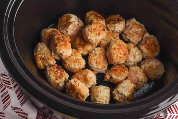 buffalo chicken meatballs in a slow cooker next to a red and white cloth