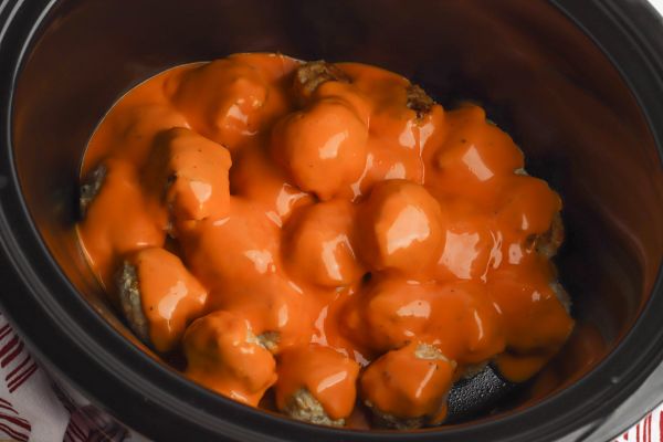 buffalo chicken meatballs in a slow cooker covered in buffalo sauce