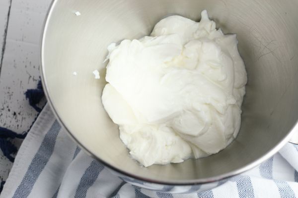 Greek yogurt in a metal mixing bowl on a striped cloth