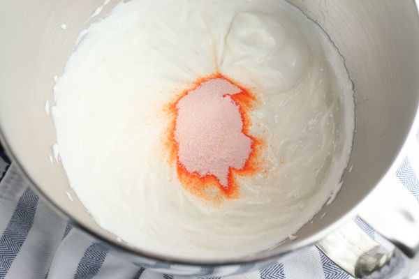 orange jello powder and Greek yogurt in a metal mixing bowl on a striped cloth