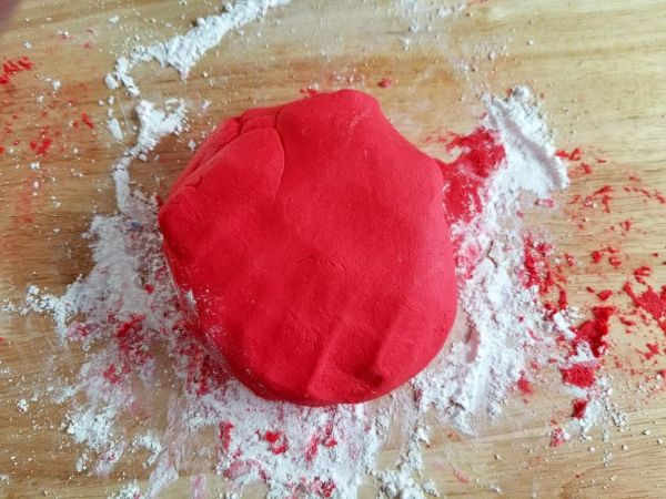 red edible play dough and powdered sugar on a brown table