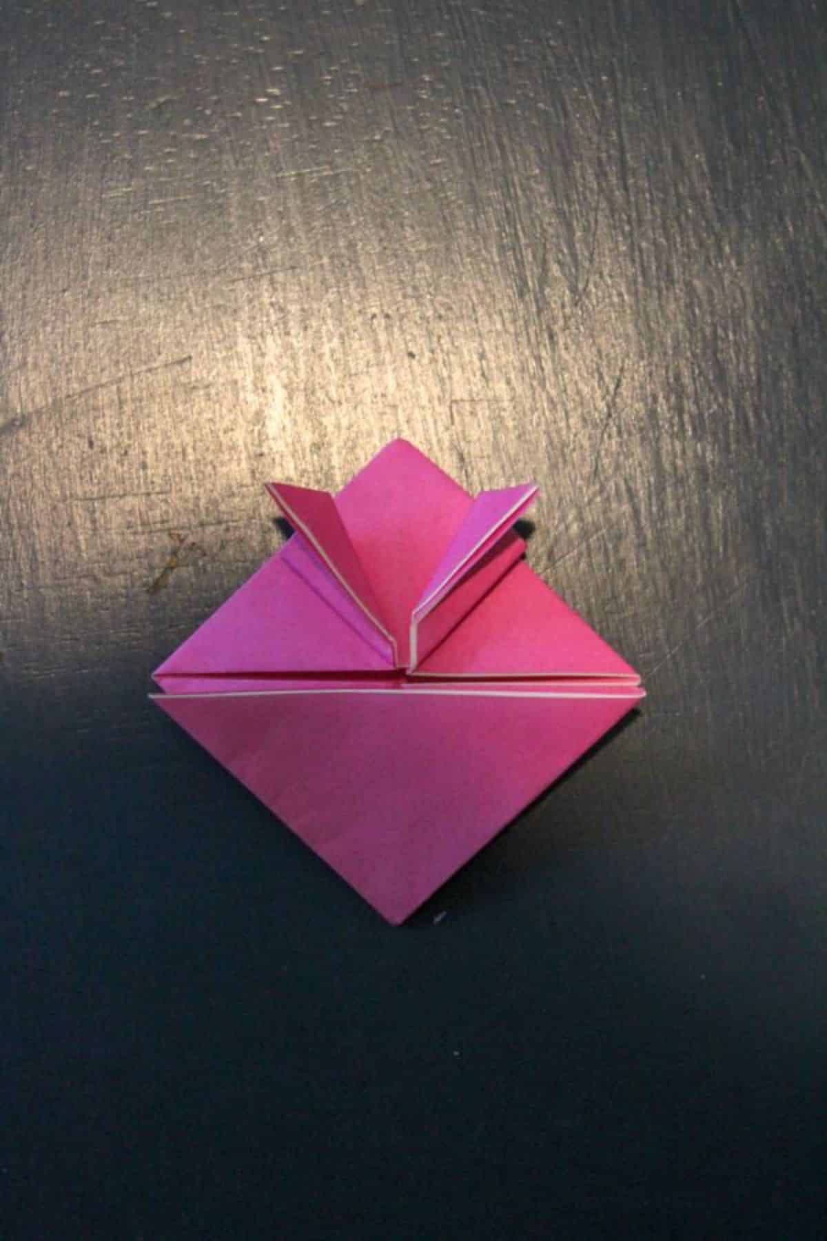 origami paper is now folded with the top part of the right side folded upwards, back down.