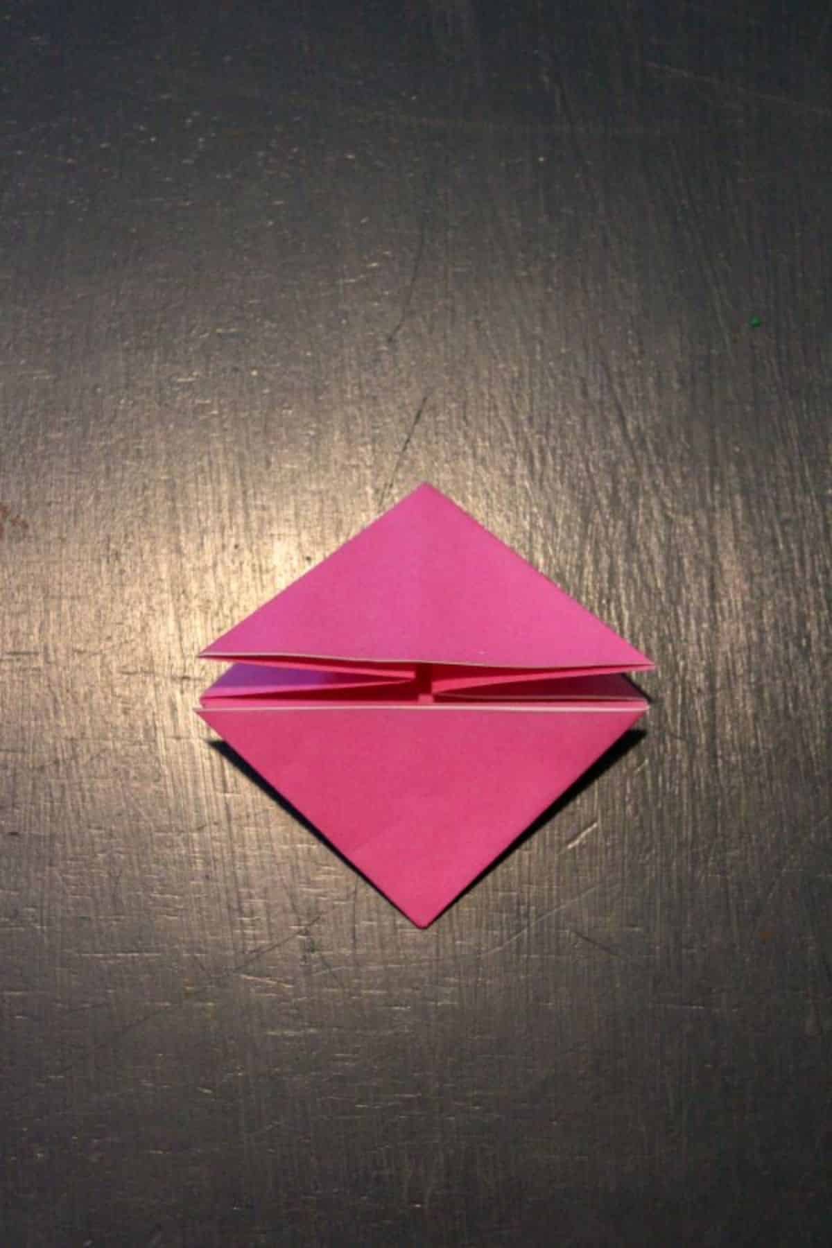 on a black background, the pink origami paper is folded up into a nice little diamond.