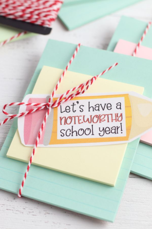 teacher notebook gift of notebook paper, a sticky note and a paper shaped like a pencil with the words Lets have a noteworthy school year on it, all tied together with red and white string