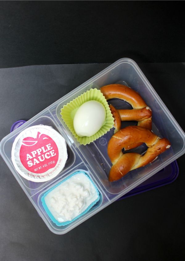 hard boiled egg lunch box with a soft pretzel and apple sauce