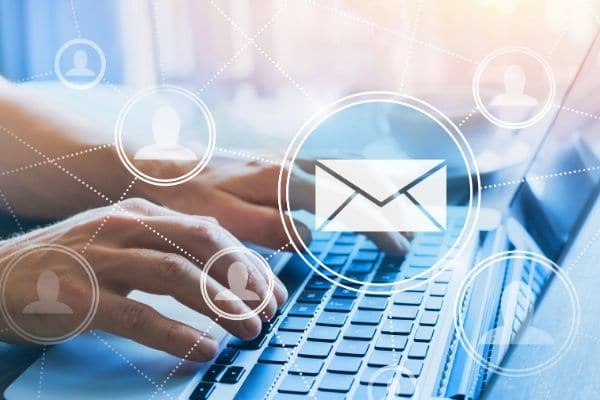 a person typing on a laptop with graphic overlay of people and an envelope