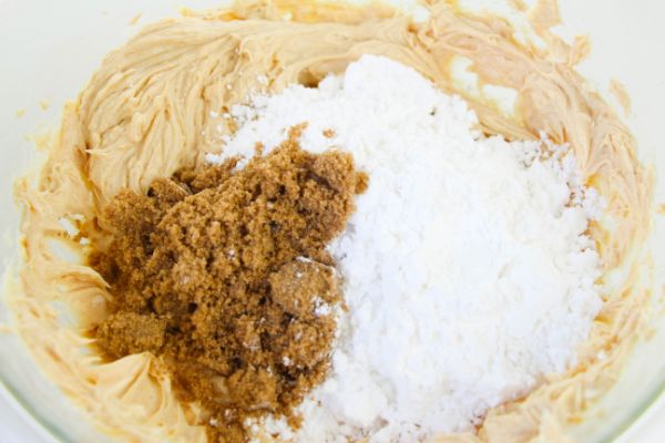 powdered sugar, brown sugar, softened cream cheese, peanut butter and butter in a large glass bowl on a white table
