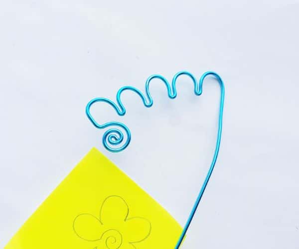 how to make a wire bookmark by swirling an end and making a scalloped line, and a yellow printable flower template on a white background