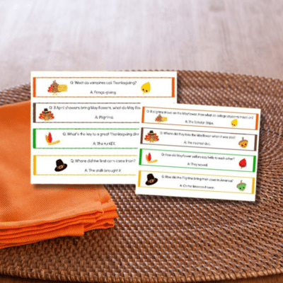 A set of printable Thanksgiving cards on a table, accompanied by festive napkin rings.