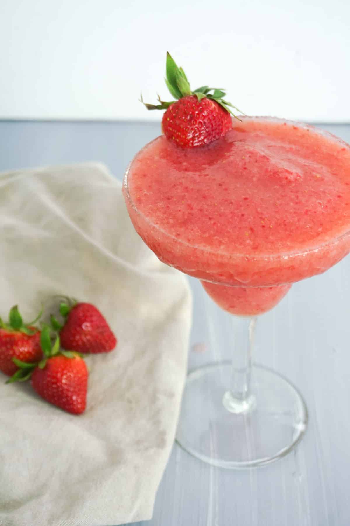 Strawberry Lemonade Margarita in a glass, garnished with strawberry.
