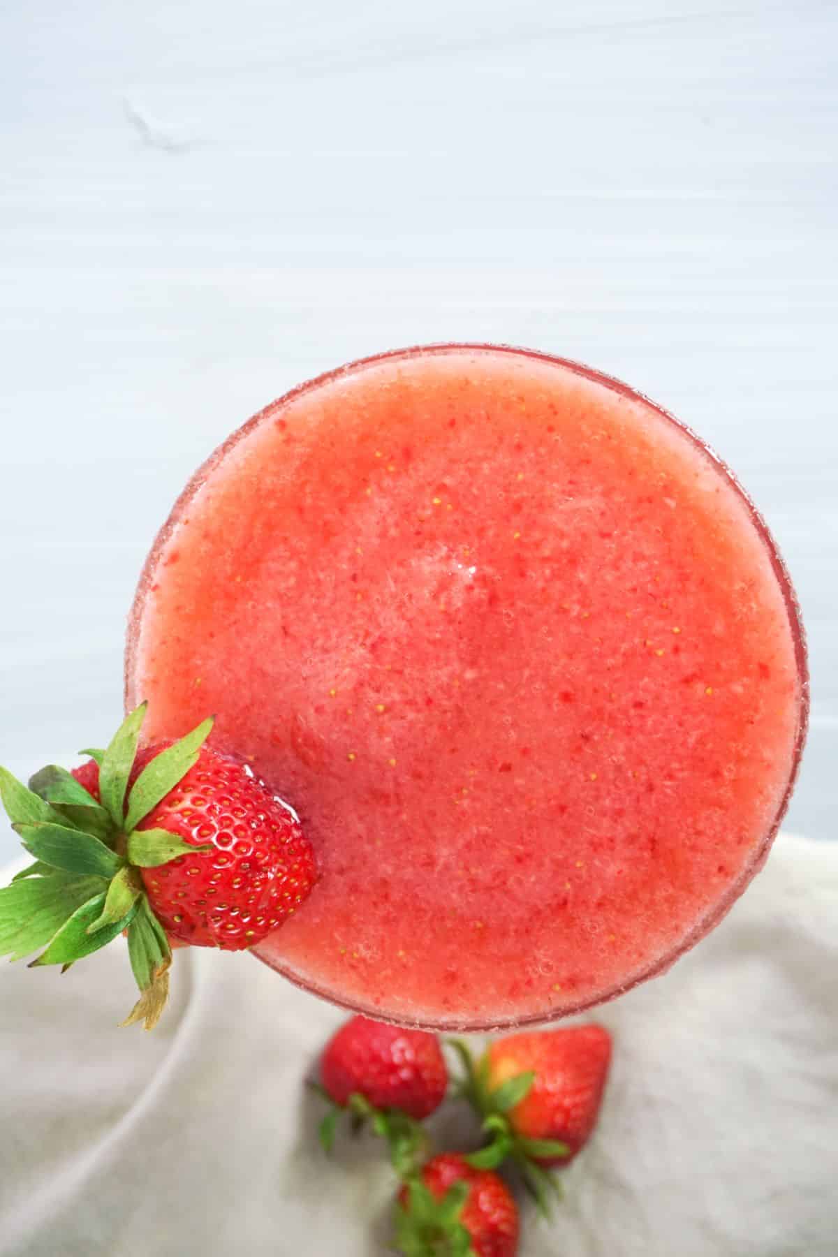 overhead view of a Strawberry Lemonade Margarita in a glass, garnished with strawberry.