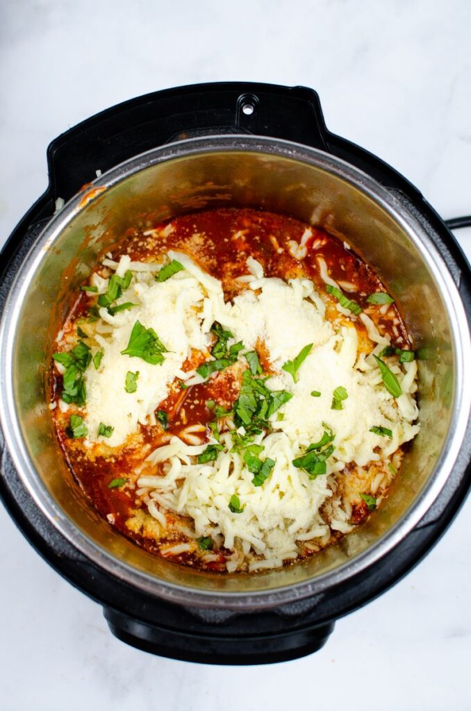 Mozarella cheese on top of chicken in a tomato sauce in an instant pot.