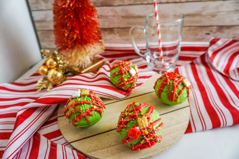 christmas hot cocoa bombs on wooden platter with tree in background