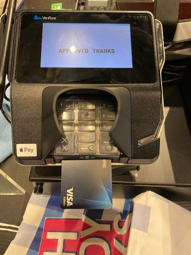 a credit card in a payment machine in a store with the words approved thanks on the screen