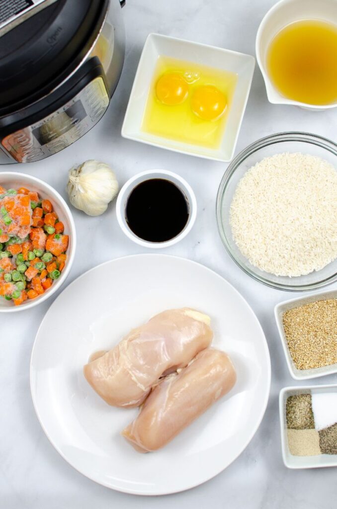 Chicken, peas, carrots,eggs and other ingredients in glass bowls next to an instant pot.