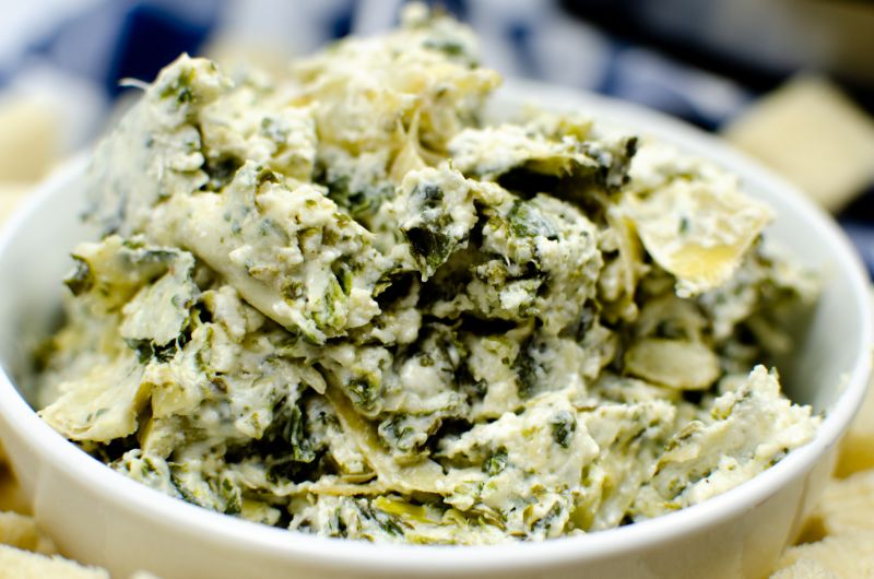A white bowl of spinach artichoke dip.