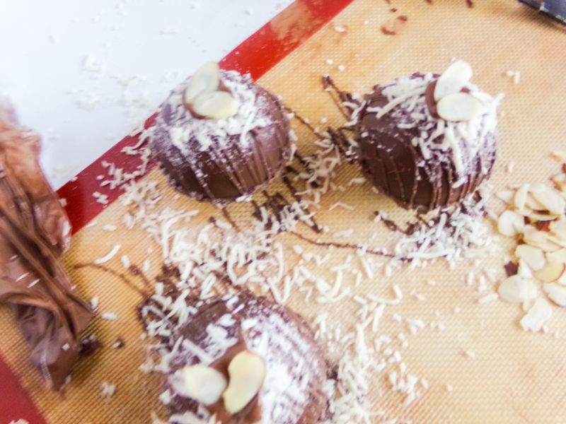hot cocoa bombs topped with melted chocolate, sliced almonds and shredded coconut