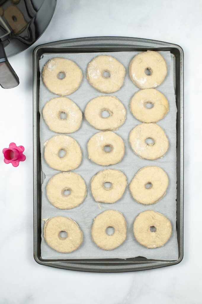 donuts on parchment paper on a baking sheet next to an air fryer