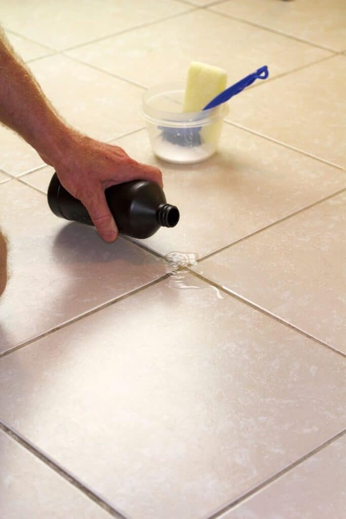 a man's hand pouring hydrogen peroxide on a tile floor 