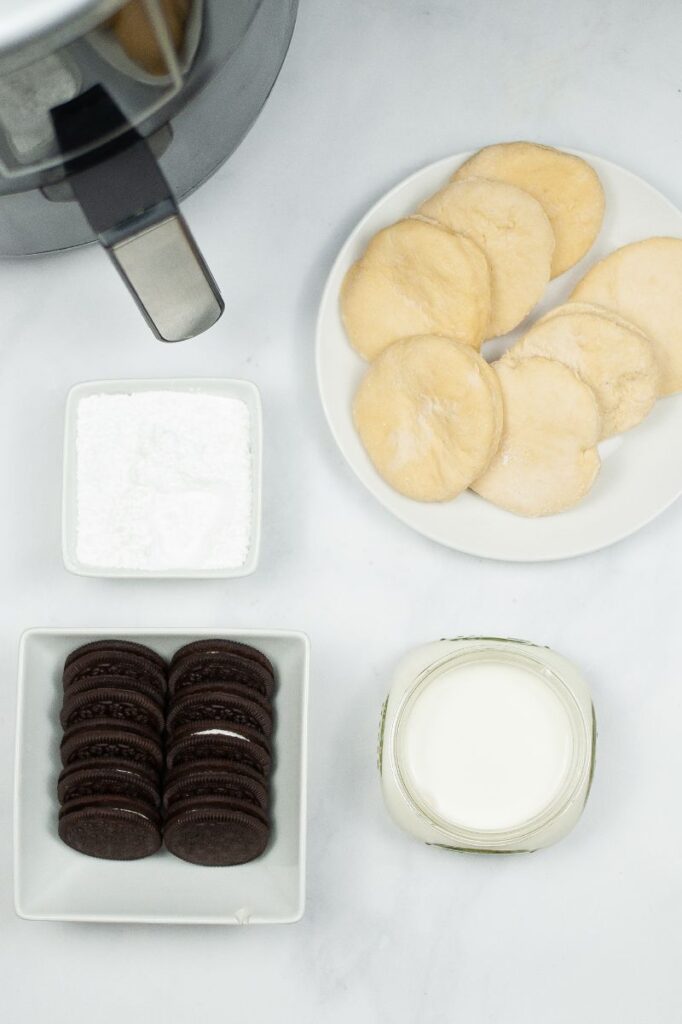 ingredients needed to make air fryer oreos and an air fryere on a white counter