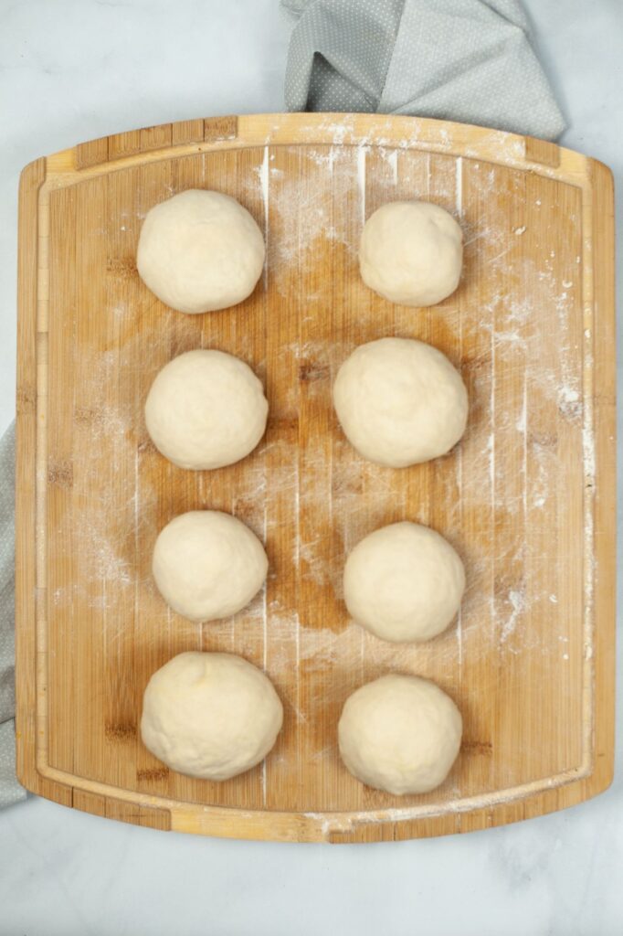 bagel dough divided into 8 balls on a wooden cutting board