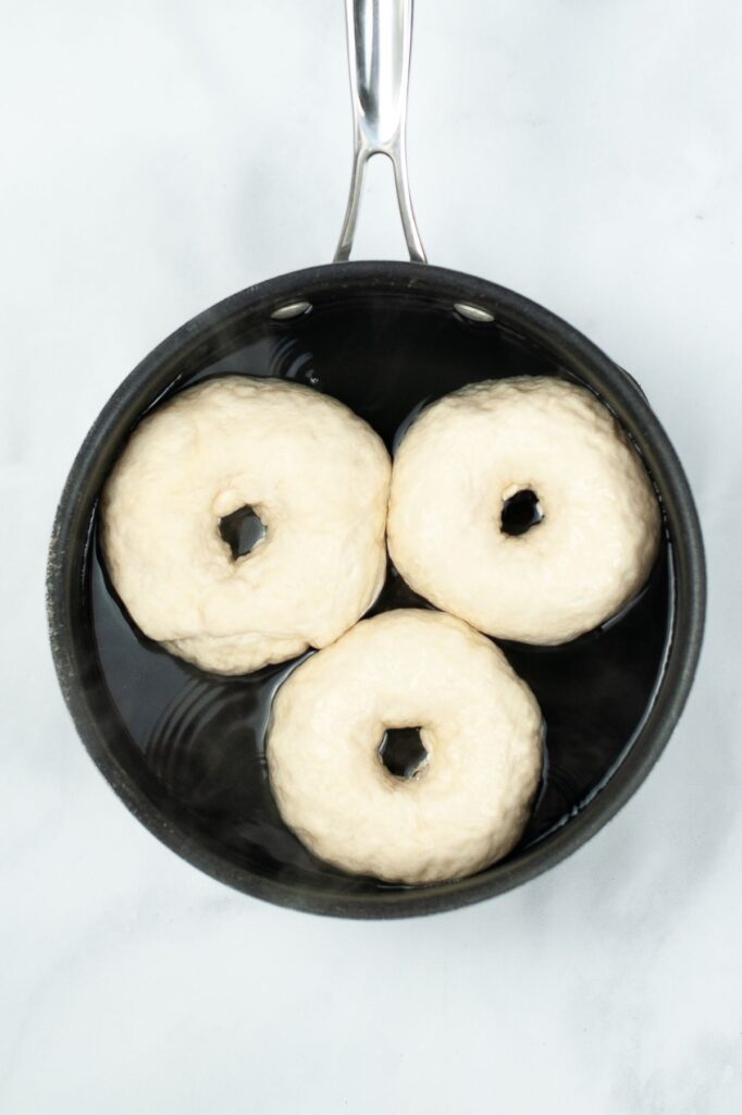 3 raw bagels in a pot of water