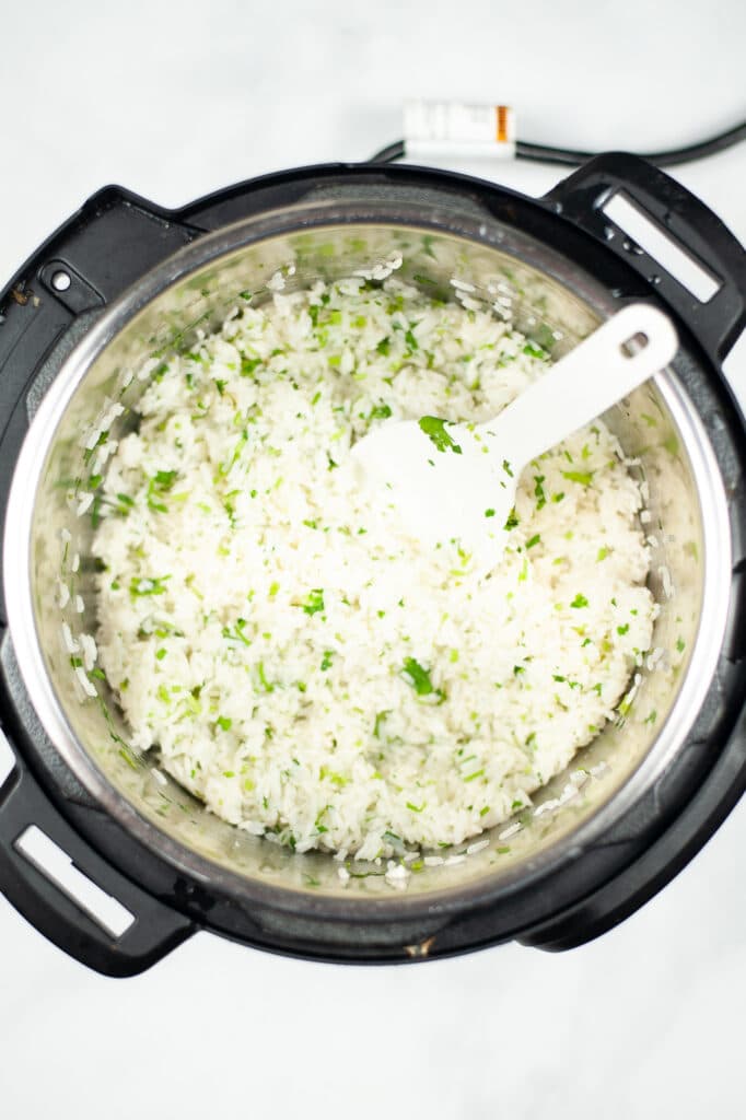 a white spoon in the instant pot to stir the copycat cilantro lime rice