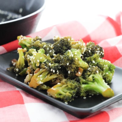 black plate full of process Asian Style Broccoli on red and white tablecloth