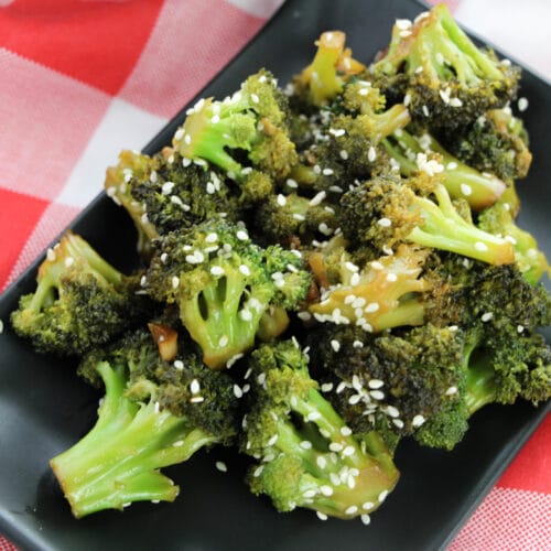 black plate full of process Asian Style Broccoli on red and white tablecloth