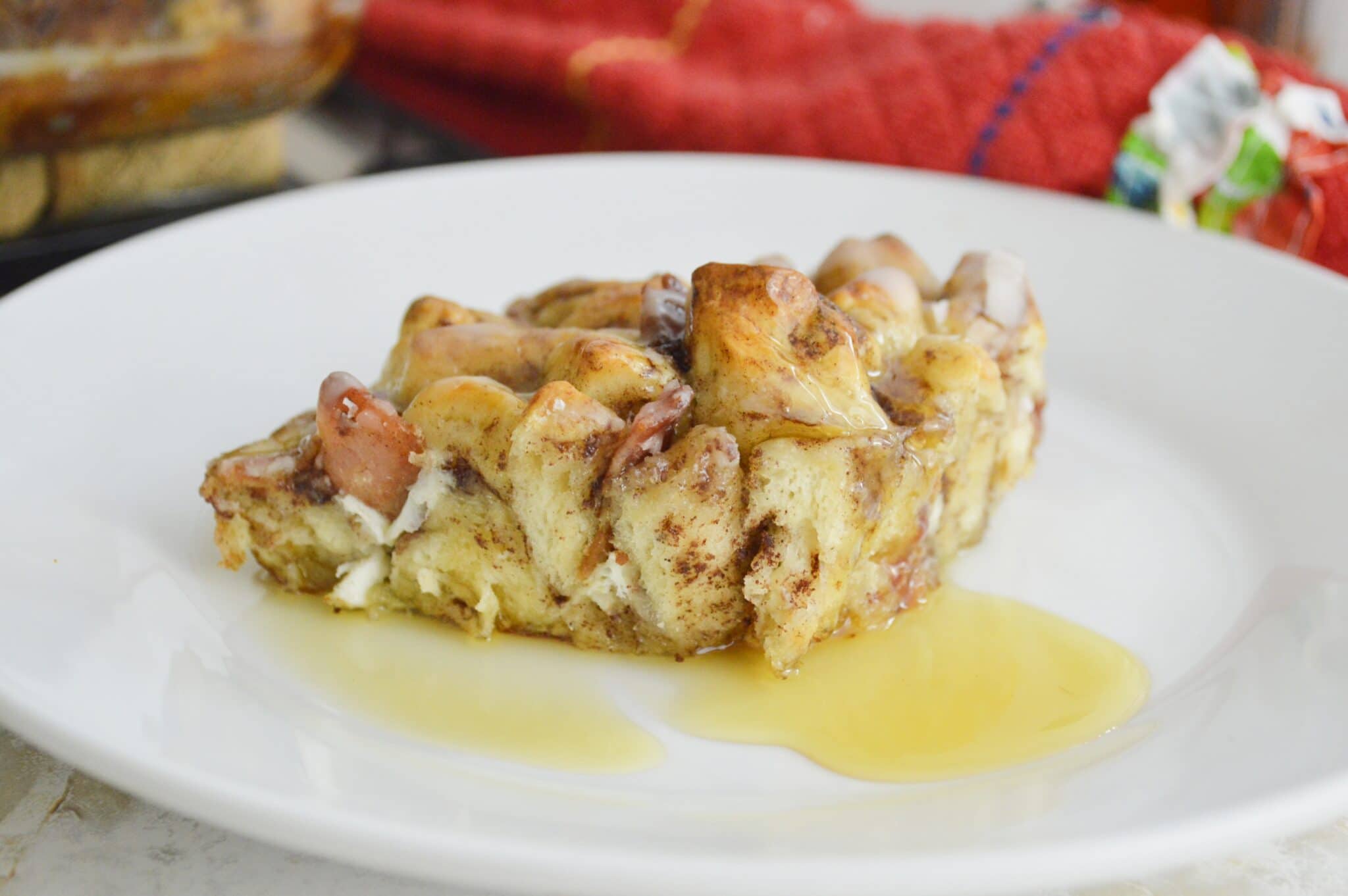close up of piece of bacon cinnamon roll casserole on white plate 