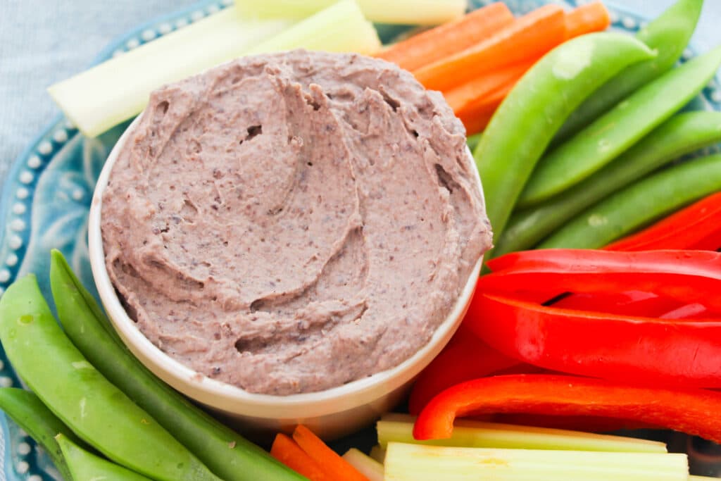black bean hummus in a bowl with cut up vegetables around it